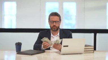 Para kazan. İş adamı ofiste dolar sayıyor. Takım elbiseli bir ofis çalışanı ve dolar. Ofis işvereni para banknotlarını tutar. Takım elbiseli adam dolar sayıyor. Para ver, para kazan.