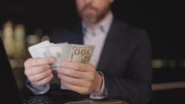 Gece sokağında para sayan adam, kapat. New York 'ta bize dolar sayıyorlar. ABD 'de finans ve bankacılık. Gece şehir geçmişinde para sayan bir iş adamı. İşadamı ABD banknotlarını saydı
