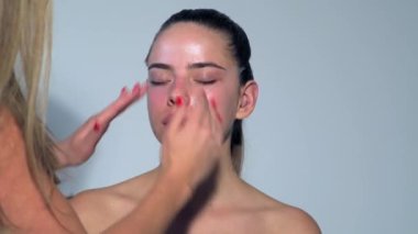 Makyaj sanatçısı makyaj fırçasıyla makyaj yapar. Güzellik abidesi. Makyaj ustası ve genç güzel kız. Telafi sürecinde. Makyaj sanatçısı tarafından makyaj yapan güzel Asyalı bir kadın.