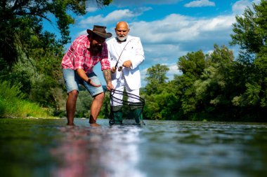 Olgun yaşlı bir adam ve balık tutan bir arkadaş. Yaz tatili. Mutlu neşeli insanlar. Sakallı adamlar balık yakalıyor. Elinde olta olan balıkçı. Etkinlik ve hobi