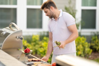 Erkek aşçı bahçede ızgara yapıyor. Barbekü açık hava bahçe partisi. Yakışıklı adam ızgara et hazırlıyor. Yaz boyunca dışarıda yemek ve yemek pişirme kavramı