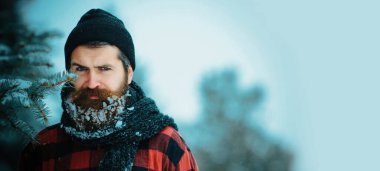 Karda sakallı ciddi bir adamın portresi. Karda sakallı kızgın bir kış adamı ciddi bir yüzle. Karlı sakallı kaba sakallı adam. Kışın karlı arka planda zalim hipster.