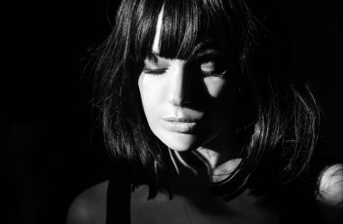 Siyah arka planda ışığı olan şehvetli bir kadın. Karanlıkta güzel bir kadın yüzü. Şefkatli ve baştan çıkarıcı bakışlar. Moda sanat stüdyosu portresi. Siyah arka planda esmer, baştan çıkarıcı bir kız.