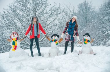 Güzel Kış Kızları grubu ve kardan adam. Öğrenci partisi ve Noel kutlaması. Kış Parkı 'nda kardan adamla eğlenen iki neşeli genç kadın. Mutlu Noeller ve mutlu yıllar.