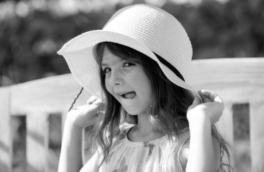 Funny kids face with tongue. Portrait of funny child girl in summer park. Face close up of cute teen girl outdoor. Cute little girl swinging on the meadow in summer day