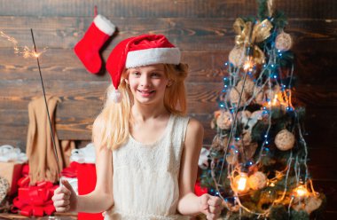 Çocuklar içeride Noel ağacının yanında eğleniyorlar. Çocuk hediyesi. Noel kartı. Mutlu küçük kızın portresi Noel ağacının yanındaki oyuncak topuna bakıyor.