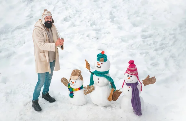 Winter scene with snowman on white snow background. Happy winter snowman family. Mother snow-woman, father snow-man and kid wishes merry Christmas and Happy New Year