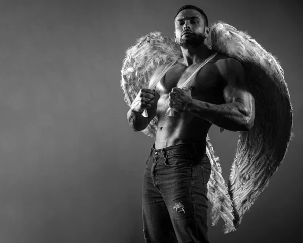 Young man with angels wings. Strong man showing his perfect naked body. Bare torso