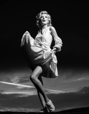 Gün batımında pembe elbiseli kadın, Monroe tarzı. Moda elbiseli güzel bir bayan. Seksi ve şehvetli bir kadın modeli.