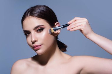 Toz fırçası. Kızların yüzü kızaracak, fırçayla toz banyosu yapacaksın, izole edilmiş bir stüdyo geçmişi olacak. Yanaklarını pudralayan genç bir kadın. Makyaj fırçası. Kadın model fırçayla allık tozu alır