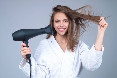 Stüdyo arka planında saç kurutma makinesi olan esmer bir kadın. Saç stili ve güzellik konsepti. Saç kurutma makinesi olan güzel bir kız. Güzellik kızı saç kurutma makinesiyle saç kurutur. Saç kurutma makinesi.