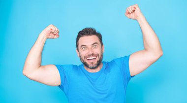 Neşeli heyecanlı adam başarıyı stüdyo mavi izole edilmiş arka planda kutluyor. Heyecanlı kazanan. Kutlama jesti ile heyecanlı yakışıklı bir adam. Heyecanlı bir adam.