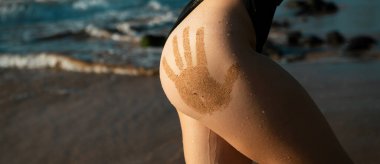 Sandy sexy womans buttocks with sand hand prints. Girls ass closeup sexy butt with hand prints at the jamaica or phuket beach. Women sensual body. Tanned booties young model
