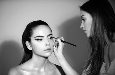 Makyöz göz farı sürüyor. Vizeci bir el, genç bir güzellik modelinin kozmetik ürünlerini boyuyor. Moda cilt üzerinde parlak fosforlu kalem. Profesyonel makyaj süreci