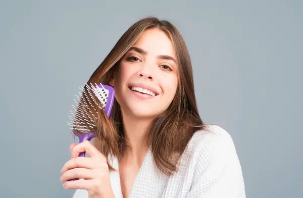 Woman combing hair. Female happy smiling model with a comb brushing hair. Girl with hairbrush, hair care and beauty. Healthy face skin, skincare cosmetology cosmetics