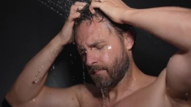 Orta yaşlı bir adam banyoda saç yıkıyor. Küvette banyo yapan adam. Yüzü duşta köpüklü. Banyo yapan adam duş alıyor. Yakından duş alan adam. Duş konsepti. İnsan duşta su altındadır.