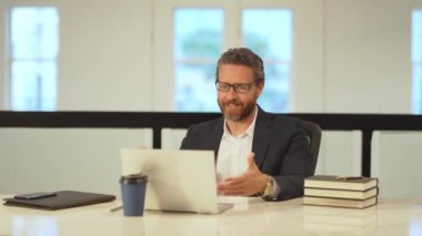 Bilgisayarlı bir ofis çalışanı web kamerasında konuşuyor. Çevrimiçi video toplantısı. Ofisteki video konferansında çalışan konuşuyor. İş adamının video görüşmesi var. İş adamı video sohbeti için dizüstü bilgisayar kullanıyor