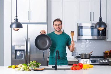 Adam mutfakta yemek pişiriyor. Şef aşçı tencereli bir yemek hazırlıyor. Menü tarifi sağlıklı yemek. Evde yemek pişiren adam mutfakta yemek hazırlıyor. Olgun bir adam mutfakta yemek hazırlıyor.