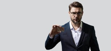 Banka kartı. Gri arka planda kredi kartı tutan bir iş adamı. İspanyol adam kredi kartını gösteriyor. Kredi kartı ya da banka kartı. İndirim teklifi, online alışveriş. Kopyalama alanı olan pankart