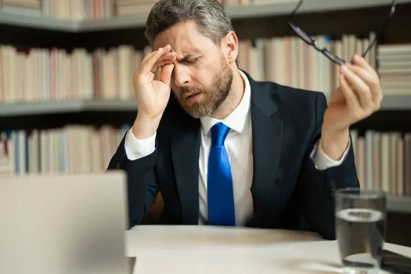 疲倦和压力 穿西装的商人用笔记本电脑 累得头疼偏头痛 头痛的概念 在办公室工作时 有痛苦的男人会感到压力 紧张和头疼 — 图库照片