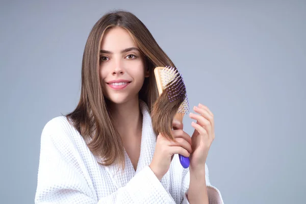 Beautiful woman with brush combing hair. Beauty girl with straight hair isolated on studio background. Woman hold hairbrush near face. Healthy hair. Hairstyle and hair care concept. Shiny hairs