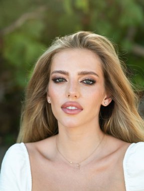 Güzel kadın yüzü. Moda tarzı yakın çekim portresi. Bahar doğası arka planında güzellik modeli. Mükemmel ciltli, makyajlı ve sarı saçlı alımlı bir kadın. Güzel açık hava portresi.