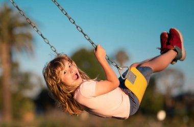 Çocuk çocuk çocuk parkında oynuyor. Çocuk parkında hareketli küçük bir çocuk. Çocuklar okulda ya da anaokulunda oynarlar. Renkli salıncakta hareketli bir çocuk. Küçük çocuk sallanıyor