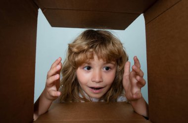 Çocuk bir kutu açıyor ve içine bakıyor, paketleri açıyor, sürpriz bir şekilde boks yapıyor. Çocuklar şaşırmış yüz ifadeleri
