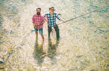 Portrait of cheerful senior man fishing. Grandfather and son fishermans. Young man and an old man fishing for spinnings on the river or lake