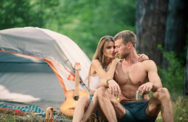 Loving young coupl hug near camp tent. Camping couple in love. Couples of lovers tourists relax on nature. Camping trip with lovers. Picnic for friends tourists