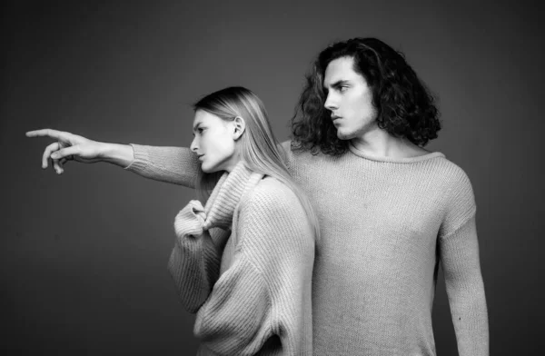 Portret of stylish confident male and female models with nature hairstyle wearing a yellow and green sweater and standing close together looking alluringly at camera