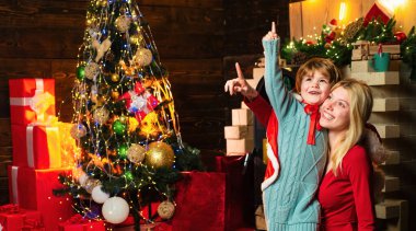 Kız kardeşi olan mutlu çocuk göster kendini. Noel 'i kutlayan şirin çocuklar. Noel kutlaması tatili. Anne ve sevgili oğlu Noel ağacı arka planında.