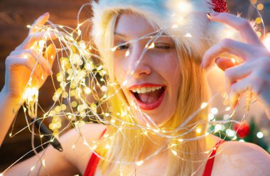 Çok fazla ışık var. Noel kutlaması. Tüm yıl boyunca barış ve sevinç seviyorum. Kız Santa şapka yılbaşı partisi. Kız yeni yıl ve mutlu Noeller kutlamak. Noel çelenk sıcak ışık. Sihirli an.