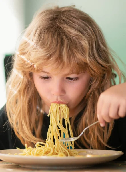 Tasty food, messy child eating spaghetti. Child have a breakfast. Tasty kids breakfast. Childcare and childhood. Close up portrait of funny kid eating noodles pasta