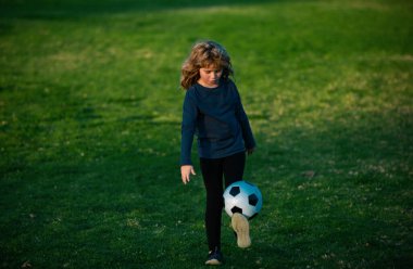 Futbol topuyla spor giyim sektöründe genç bir futbolcu. Küçük çocuk kaleye ateş ediyor, çocuk futbol topunu tekmeliyor