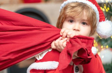 Noel Baba çocuk Noel 'i evde kutluyor. Noel hediyeleri getirdim. Kocaman kırmızı çantalı, hediyeli komik küçük Noel Baba. Noel Baba hediye dolu çanta taşıyor.