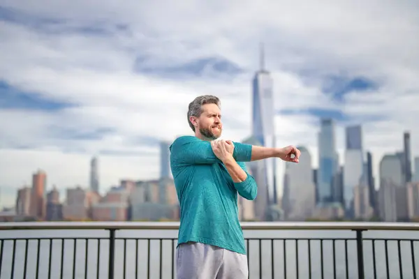 外で腕を伸ばすスポーツウェアの成熟した男 ニューヨーク市の屋外で演習をする男 ニューヨーク市でのハッピーマンワークアウト フィットネス 運動のためのシニアランナーの動機 — ストック写真