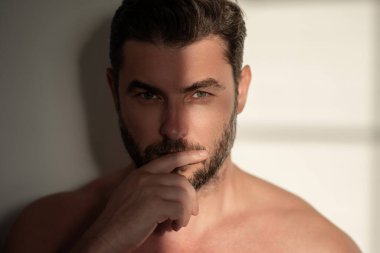 Kozmetik, vücut bakımı ve spa tedavisi. Beyaz arka planda izole edilmiş erkeksi, çekici, üstsüz bir adam portresi. Çekici adamın yakın plan portresi.