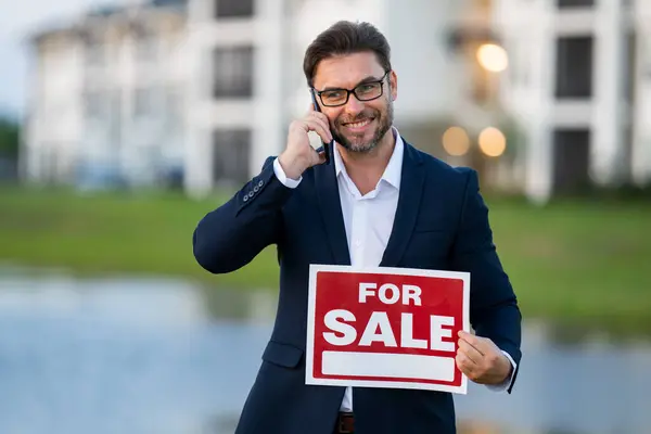 House for sale. Real estate purchase and sale concept. Real estate services. Confident business man in suit, real estate agent, professional realtor offering new dwelling real estate house to buyer