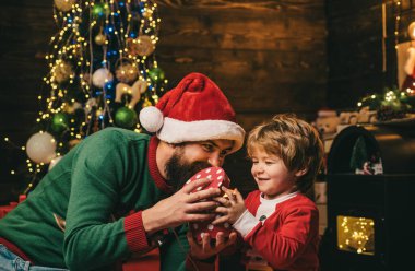 Yeni Yılınız Kutlu Olsun. Baba ve oğul internet kullanıyor. Küçük Noel Baba ve yaşlı sakallı Santa dizüstü bilgisayar kullanarak