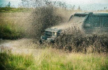 Kırsalda yağmurdan sonra geçilemez yolda kalan bir off-road aracı. Kirli arazi aracı yarışı. Off-road yarışında su sıçradı