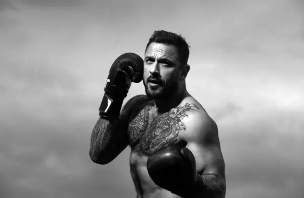 Athlete boxer punching. Portrait of male boxer. Muscular man in boxing gloves outdoor. Athletic boxing fighter. Boxing training outside