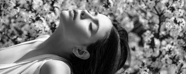 Baharı hisseden güzel kız. Bahar güneşli bir gün. Bahar bahçesinde doğanın tadını çıkaran güzel genç bir kadın. Sancak bahar tasarımı, web sitesi başlığı reklamı