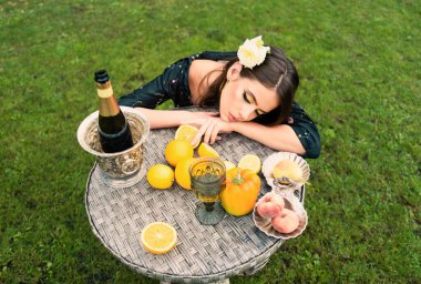 Parktaki bir masada taze meyveli seksi bir kadın. Sağlıklı vejetaryen yemekleri, sağlık hizmetleri. Şehvetli genç kadın ve sağlıklı vejetaryen yemekleri, meyveler.