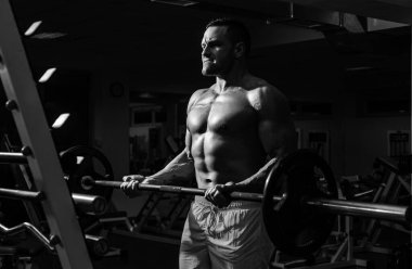 Spor salonunda dambılla egzersiz yapan genç sporcunun portresi. Crossfit, spor ve sağlıklı yaşam tarzı konsepti.