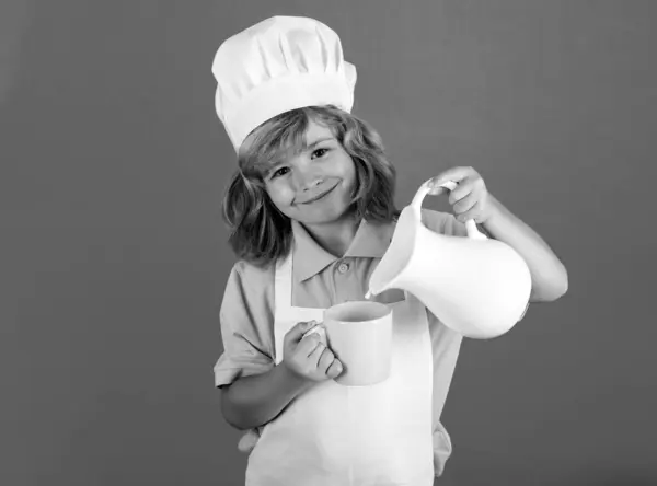 给孩子们的牛奶儿童厨师在孤立的蓝色工作室背景下做饭 小孩子在做饭一个戴着围裙和厨师帽的少年在厨房里准备健康的蔬菜餐 — 图库照片