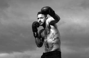 Boks eldivenleriyle poz veren sert erkek boksörün portresi. Profesyonel boks maçı için hazır. Sporcu Muay Thai boksör dövüşü. Güçlü kaslı boksör.