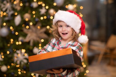 Noel Baba çocuk. Noel Baba şapkalı mutlu çocuk elinde Noel hediyesi tutuyor. Noel 'de mutlu çocuk. Şaşkın çocuk yeni yılı kutluyor. Noel çocuğu