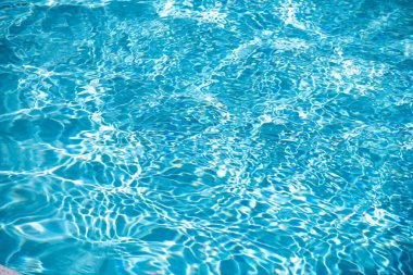Su arka planı, dalgalanma dalgaları. Mavi yüzme havuzu deseni. Deniz yüzeyi. Yüzme havuzunda su ve güneş yansıması. Kopyalama alanı olan pankart