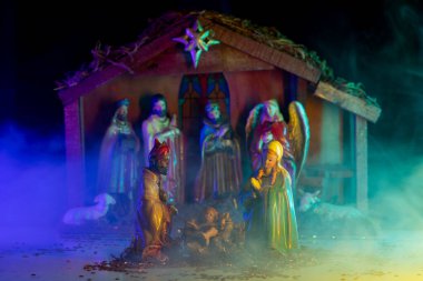 Kutsal aile ile Noel dekoratif kreşi. İçinde İsa, Meryem, Yusuf ve kuzunun da olduğu heykelciklerin olduğu bir Noel ahırı sahnesi. İncil 'deki Meryem İsa' yı tutuyor. Noel teması